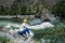 A girl sitting on the stone among the mountains and looking at the river. Woman sits near the mountain river enjoy the view