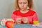 Girl sitting at a table with an apple and learning to knit