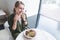 Girl sitting at a table in a bright restaurant near the window and looking at the camera smiling