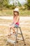 Girl sitting on top stepladder outdoors