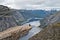 Girl sitting on Trolltunga rock and looking at Norwegian mountain landscape