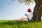 Girl sitting under a blossom tree reads a book