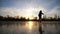 Girl skating on frozen river during beautiful sunset. Young woman shod in figure skates sliding on ice. Shining sun is