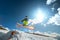 Girl skier in flight after jumping from a kicker in the spring against the backdrop of mountains and blue sky. Close-up