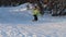 Girl skier in yellow slides down from hill and falls at winter day