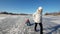 Girl sledding sister on frozen lake