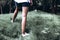 Girl with slender tanned legs walking in the park on the green grass