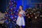 Girl in a smart white dress at the Christmas tree