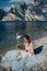 A girl in a smart white dress is sitting on the embankment of lake Garda.A woman is photographed against the background of a