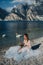 A girl in a smart white dress is sitting on the embankment of lake Garda.A woman is photographed against the background of a