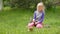 Girl smashes coconut with a heavy iron hammer sitting on the grass 01