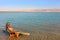 Girl smeared with therapeutic mud sunbathes, Dead Sea