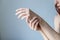 Girl smears her hands with a scrub. Gentle skin care concept, on blue background