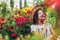 Girl smelling and admiring roses. Woman gathering flowers in garden for bouquet. Summer gardening