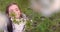 Girl smelling the  aroma of blooming spring trees in apple orchard. Bulgarian woman in folklore dress in garden