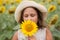 Girl smelling sunflower in the summer field at cloudy day