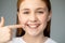 The girl smiles and shows her uneven teeth with a finger. Dental medicine and healthcare