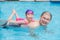 Girl smiling happily on her father back in swimming pool