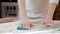 The girl smooths the dough with her hands on the table, making sure that it is even