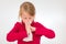 A girl is sneezing into a white handkerchief. She is 7 years old and wears a red pullover.
