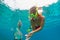 Girl in snorkeling mask dive underwater with tropical fishes