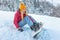 Girl snowboarder sitting alone in the snow on hill mountain outdoor, winter sport activity, equipment injury pain