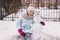 Girl and snowman. A cute teenage girl in a winter knitted hat and a blue down jacket with her friend the snowman