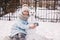 Girl and snowman. A cute teenage girl in a winter knitted hat and a blue down jacket with her friend the snowman