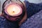 Girl in soft warm dark blue knitted sweater holds in hands burning candle