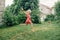 Girl splashing with gardening hose sprinkler on backyard on summer day