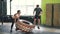 Girl in sports outfit lifting and flipping heavy rubber tyre working out with coach in gym