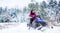 Girl on a sports snowmobile in a mountain forest. Athlete rides a snowmobile in the mountains. Snowmobile in snow