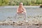 Girl in sports uniforms makes a stretch on the river bank