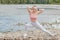 Girl in sports uniforms makes a stretch on the river bank