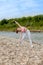 Girl in sports uniforms makes a stretch on the river bank