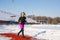 Girl in sportswear run on the red track for running on a snow-covered stadium Fit and sport lifestyle. Run and listening music.