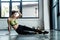 Girl in sportswear sitting on fitness mat in gym