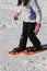 Girl with sportwear and orange snowshoes in winter