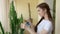 Girl spraying plant indoors.