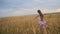 Girl spread her arms like wings and walks across field. Slow motion.