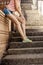 The girl on the stairs in athletic shoes in vintage toning.