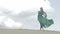 Girl stand in green dress on sand dune while wind