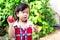 Girl stand holding a red apple that she had partially eaten. Children is wearing a red dress. Kid in a good mood.