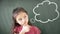 girl standing against chalkboard with thinking bubble