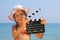 Girl standing on beach and holding clapboard