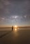 Girl standing on the beach stargazing casting long shadow from the moonlight.