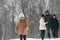 Girl is standing in front of his parents and brother. Happy family is outdoors, enjoying snow time at winter together