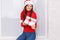 A girl is standing with a gift wrapped against a white background