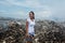 Girl standing and looking a side sad with trash around at garbage dump