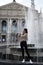 Girl standing near the fountain. Old architecture. Lviv, Ukraine. Vertical frame